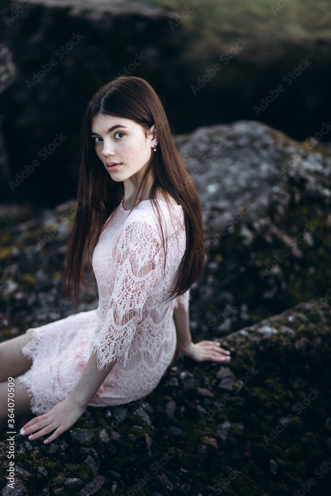 Young brunette girl portrait outdoors in grey mountains outdoors. Woman beauty concept
