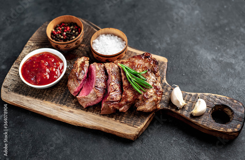  Grilled beef steak with spices served on a cutting board on a stone background