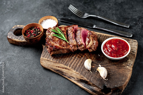 
Grilled beef steak with spices served on a cutting board on a stone background