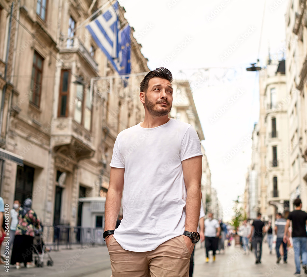Fototapeta premium Young man without surgical mask face protection on crowded street in the city walks with backpack. Crowded. Tourism