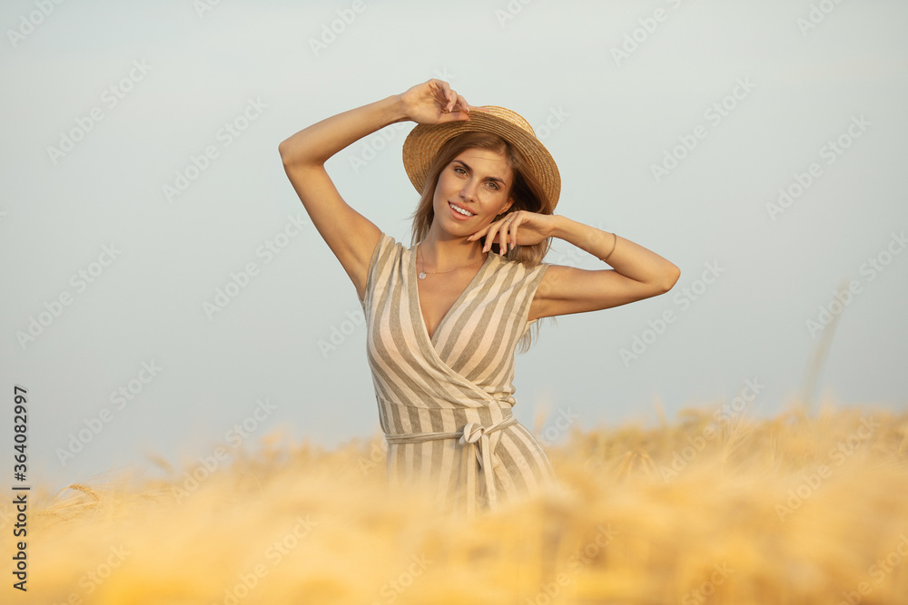 Obraz premium Beautiful carefree woman with hat in wheat meadow