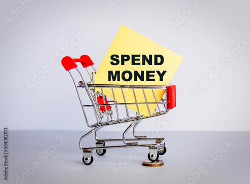 Trolley and the inscription SPEND MONEY on a yellow sticker. The concept of sales and purchases.