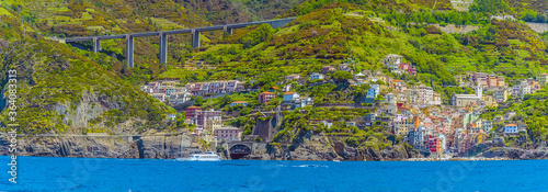 A panorama view towards the two halves of the Cinque Terre village of Riomaggiore, Italy and surrounding cliffs in summertime