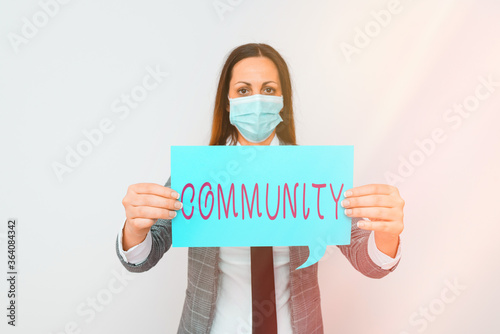 Conceptual hand writing showing Community. Concept meaning group of showing with a common characteristics living together Promoting health awareness with precautionary medical equipment photo