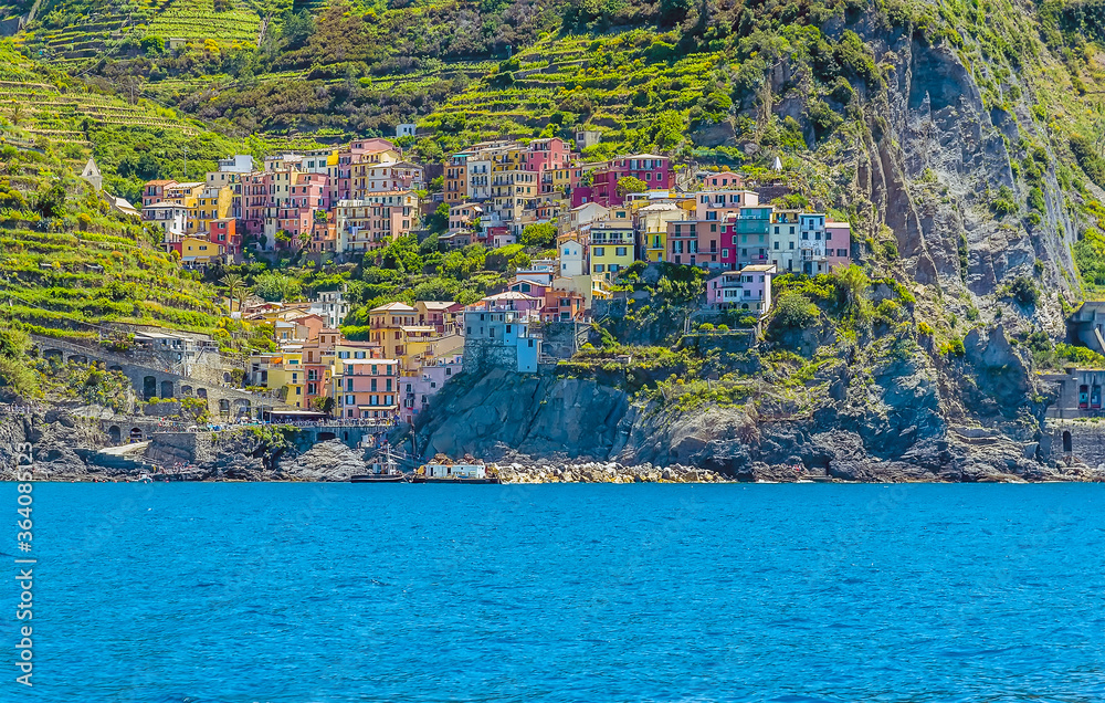 The brightly coloured buildings of Manarola, Italy slope down towards the sea in summertime