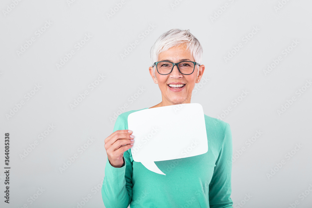 Happy mature woman in plain blue long sleeve t-shirt holding empty speech bubble isolated on background. Woman showing sign speech bubble banner looking happy Happy mature woman in plain blue long sleeve t-shirt holding empty speech bubble isolated on background. Woman showing sign speech bubble banner looking happy