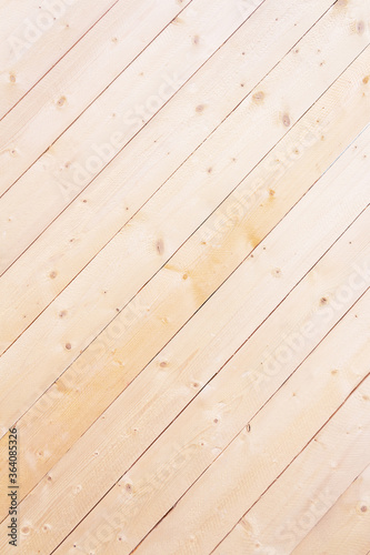 Diagonal wooden lining background. Bleached wooden texture. New wooden boards on wall. Close-up. Striped background of diagonal narrow wooden boards without varnish.
