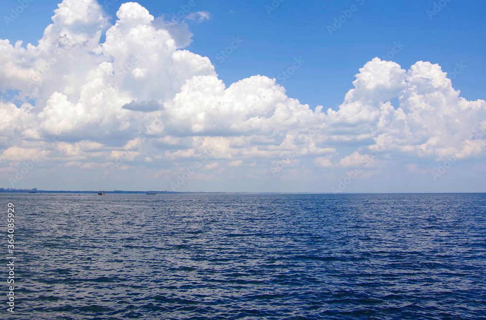 Fototapeta premium Seascape. Blue sea and thick white clouds.