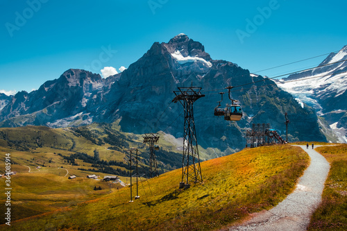 Cable car from Grindelwald to First near the top station in summer and panoramic view on snow capped mountains and glaciers in the background. Jungfrau region, Bernese Oberland, Switzerland