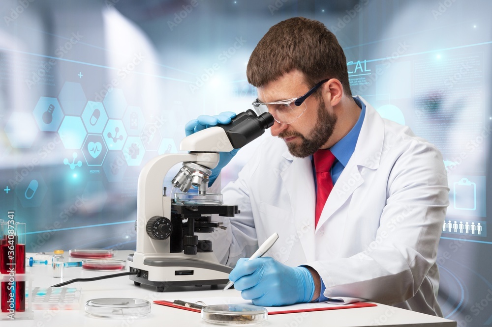 Young scientist man looking through a microscope in a laboratory. Young scientist man looking through a microscope in a laboratory.