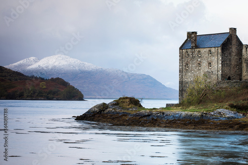 Eilean Donan Castle during colourful sunrise - Dornie, Scotland - United Kingdom. Mountains with snow in background.