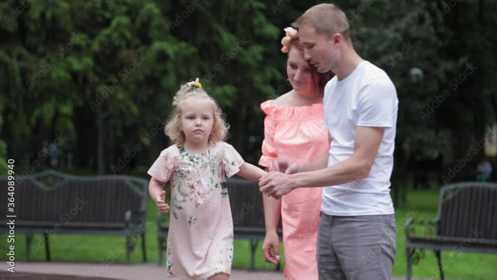 A young family with a child walks at the fountain.