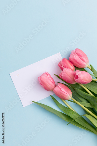 Fototapeta Naklejka Na Ścianę i Meble -  tulips and a blank gift card on blue background. flat lay.