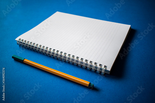 Open notepad with yellow pen on blue background