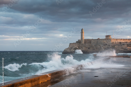 Big waves on Malecon streets during sunrise with storm clouds in background. Havana, Cuba