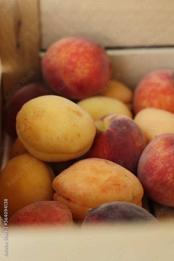 Ripe peaches and apricots in a wooden box