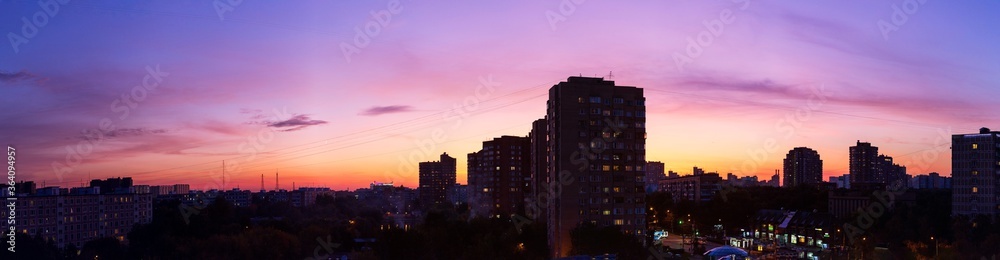 Pink orange purple sunset over the city. Multicolored sky and black silhouette of tall buildings of the metropolis