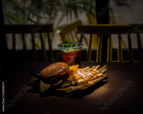 Berger with fries and nachos and a drink in a spotlight