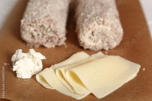 Uncooked meat roulade. Rolled meat with a filling of cheese and ham.