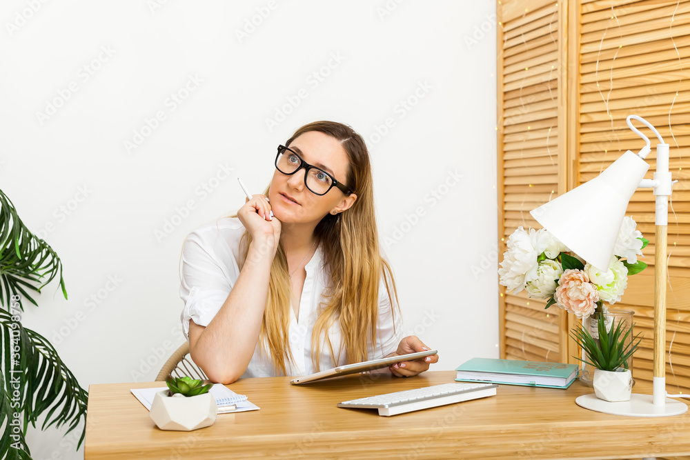 Concentrated young businesswoman working on tablet in bright office Concentrated young businesswoman working on tablet in bright office