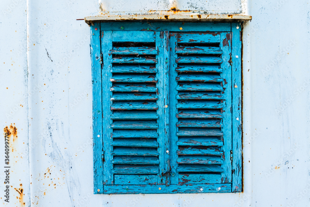 Old wooden window painted blue with rusty lock. Texture, wall of an old wooden house with shuttered windows, painted blue. Old wooden window painted blue with rusty lock. Texture, wall of an old wooden house with shuttered windows, painted blue.