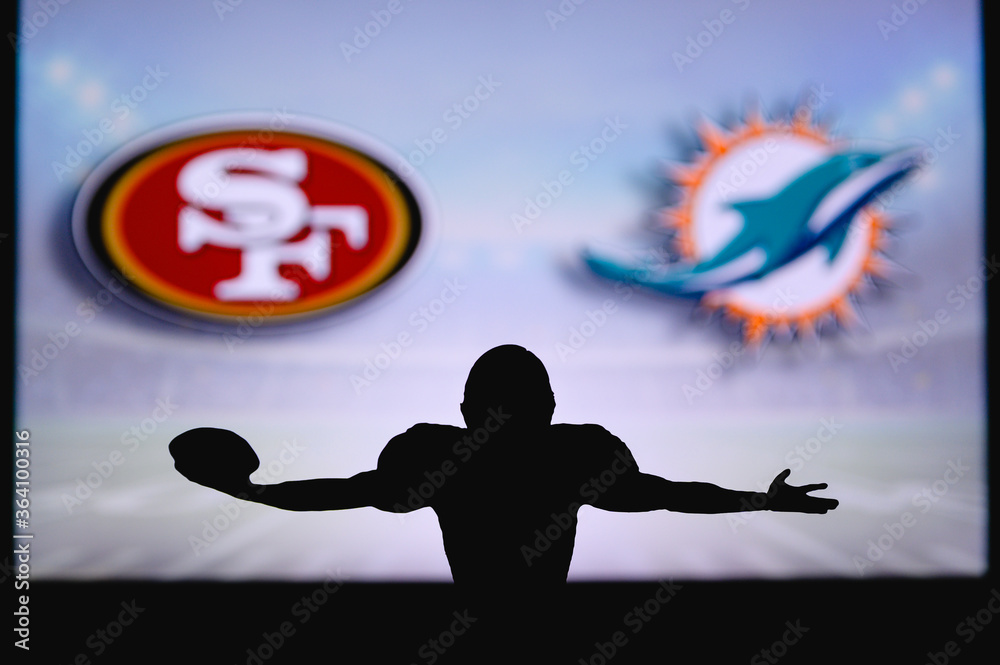 San Francisco 49ers vs. Miami Dolphins. NFL Game. American Football League  match. Silhouette of professional player celebrate touch down. Screen in  background. Stock Photo