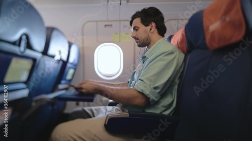 Wallpaper Mural An attractive man sits alone in an airplane and holds a smartphone in his hands. Wireless technologies in civil aviation. A tourist is sitting on a sofa in an airplane. Torontodigital.ca