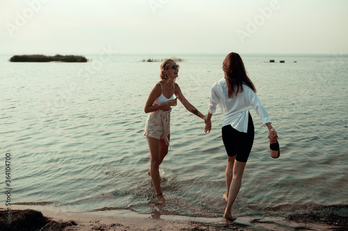 lesbian couple have fun on beach Beautiful women friends happy relax near sea when sunset in evening Lifestyle lesbian couple travel on beach concept.