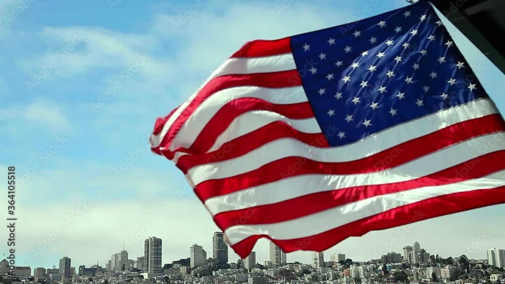 San Francisco Financial District skyline and Oakland Bridge on sunny day, California, United States. Sea views from the ship to Alcatraz island with American flag waving. Freedom and travel concept.