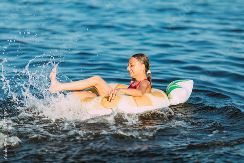 Happy child on an inflatable circle floating on the sea, Summer holidays with children. Swimming equipment and clothing for children. A little girl is floating on an inflatable circle © Shopping King Louie