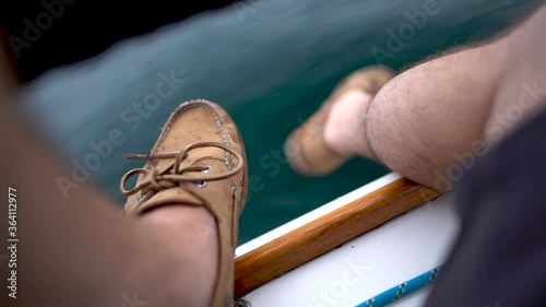 Sailing legs hanging on side of sailboat