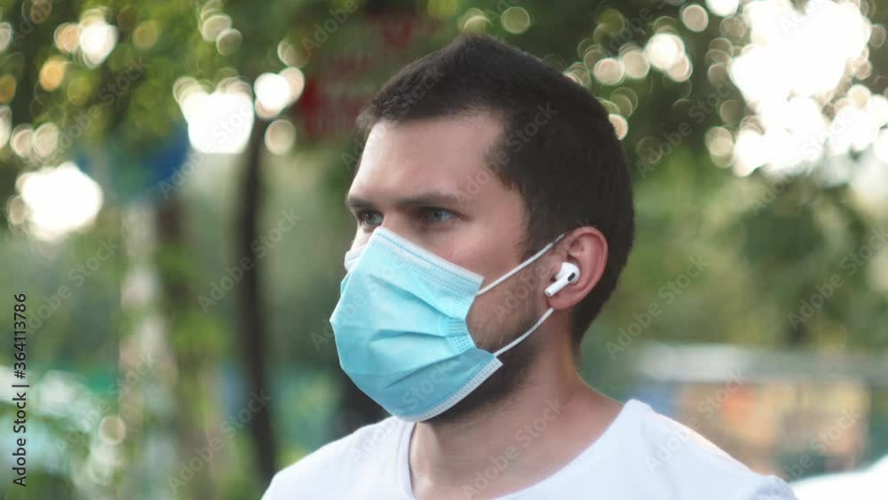 male man with wireless headphones in a medical protective mask online listening music during self isolation and quarantine. Coronavirus outbreak, flu epidemic and covid ncov male man with wireless headphones in a medical protective mask online listening music during self isolation and quarantine. Coronavirus outbreak, flu epidemic and covid ncov