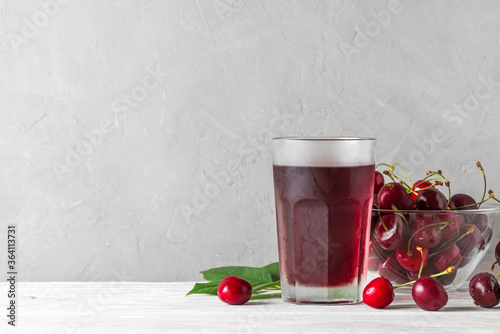 Cherry juice in a glass with fresh berries on white background. Refreshment summer drink