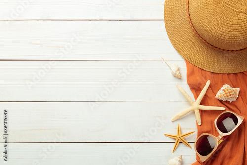 Summer background with beach accessories - straw hat, sunglasses, towel on white wood table background top view with copy space.