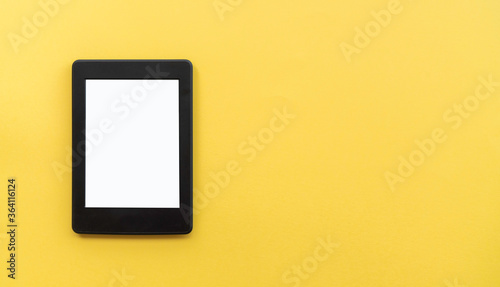 A modern black electronic book with a white blank empty screen on yellow background with empty space photo