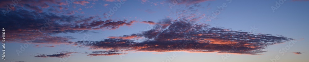 beautiful panoramic photo of the blue sky and clouds painted pink by the sunset
