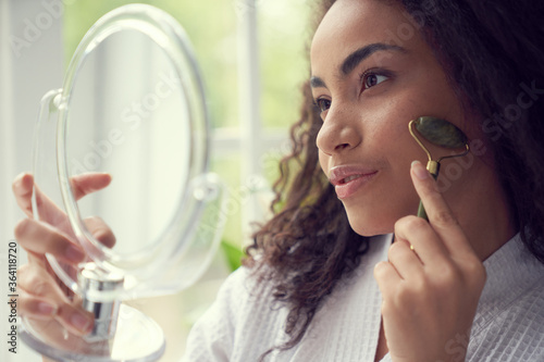 Young woman using jade roller at home