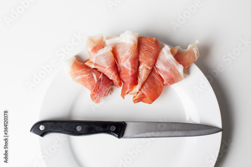 Spanish ham and a knife on a white plate photo