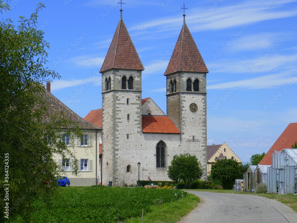 Kirche St. Peter und Paul auf der Insel Reichenau am Bodensee mit einer Radlerin im Vordergrund