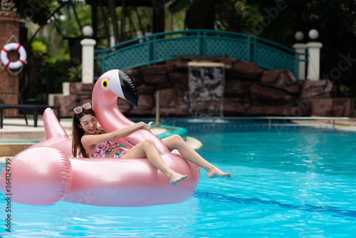 Young Asian woman relax on pink giant inflatable flamingo pool.  © May Chanikran