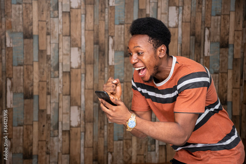 young african man holding his mobile, feeling excited and joyous
