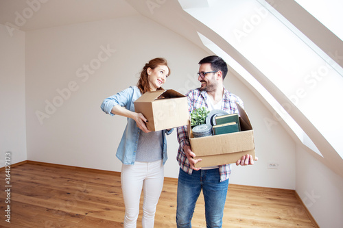 Couple with carton boxes on hands in empty room in new house