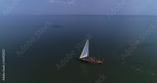 Young boys and girls are dancing on a white sail yacht in the ocean. Party on the ship. Aerial shot in slow motion photo