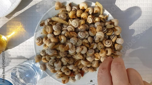 Top view of Hands taking small cooked snails. A Typical portuguese appetizer