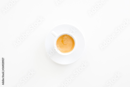 White cup of espresso coffee on a white table