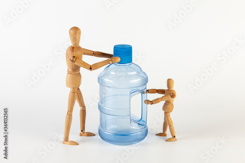Two wooden men аre holding  an empty five gallon plastic water bottle. Isolated on a white background.