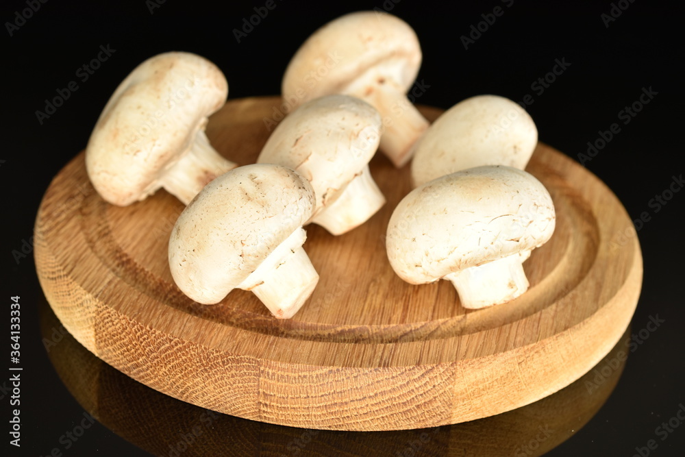 Fresh mushrooms on a wooden board, close-up, on a black background. Fresh mushrooms on a wooden board, close-up, on a black background.