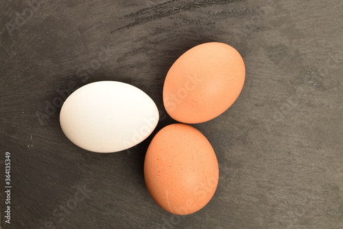 Three chicken eggs, close-up, on a slate board.