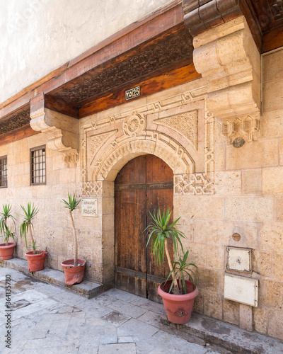 Angled view of old stone bricks decorated wall with arched wooden door, Entrance of old Ottoman historic house of Moustafa Gaafar Al Selehdar, Moez Street, Old Cairo, Egypt photo