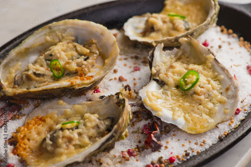 Oysters Rockefeller. Oysters topped with cheese, cream, garlic onions oven baked and garnished with fresh diced jalapeños. Classic American restaurant or French bistro appetizer. Oysters Rockefeller. Oysters topped with cheese, cream, garlic onions oven baked and garnished with fresh diced jalapeños. Classic American restaurant or French bistro appetizer.